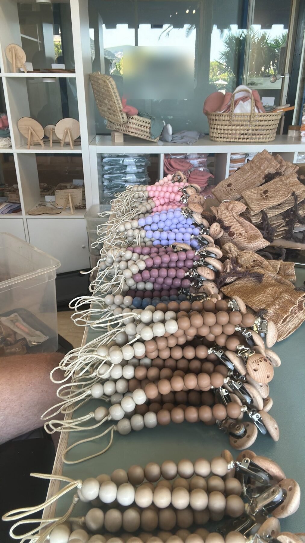 Attaches-tétines en perles de bois et silicone alignées sur un comptoir d’atelier