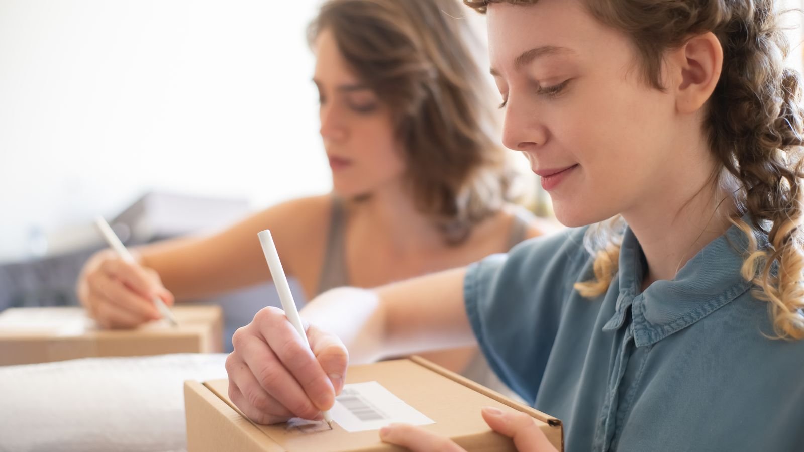Deux personnes annotent un carton dans un atelier d'exp&eacute;dition