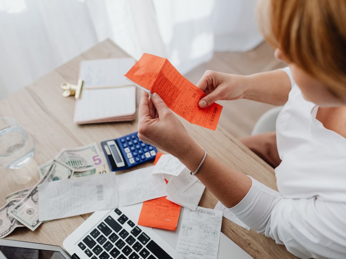 Une femme verifie des recus avec une calculatrice a son bureau