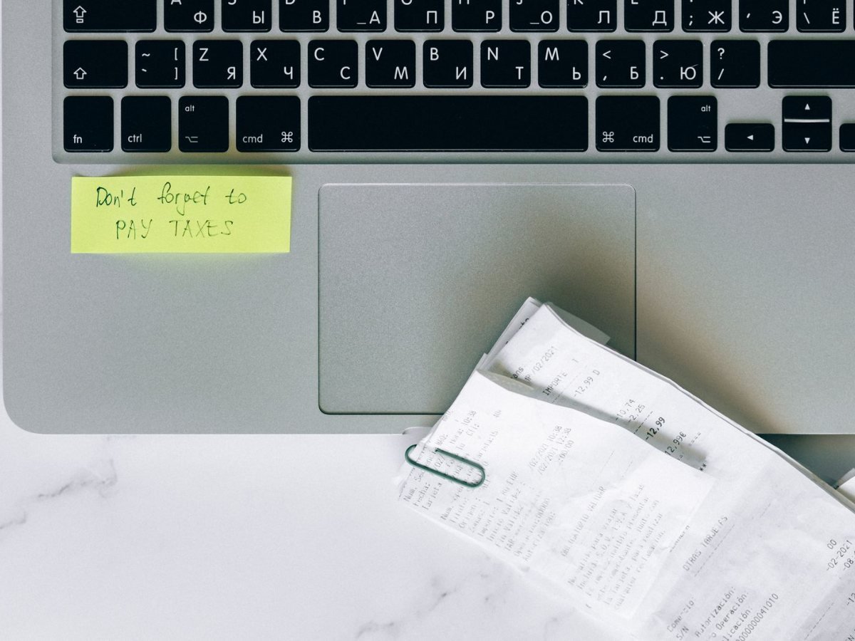 Un ordinateur portable avec un post-it de rappel et des recus