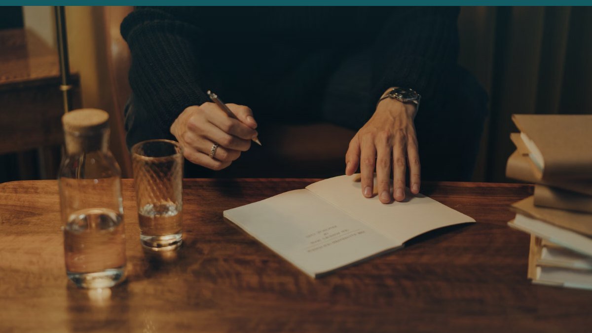 Des mains ecrivent une lettre sur une feuille posee sur un bureau
