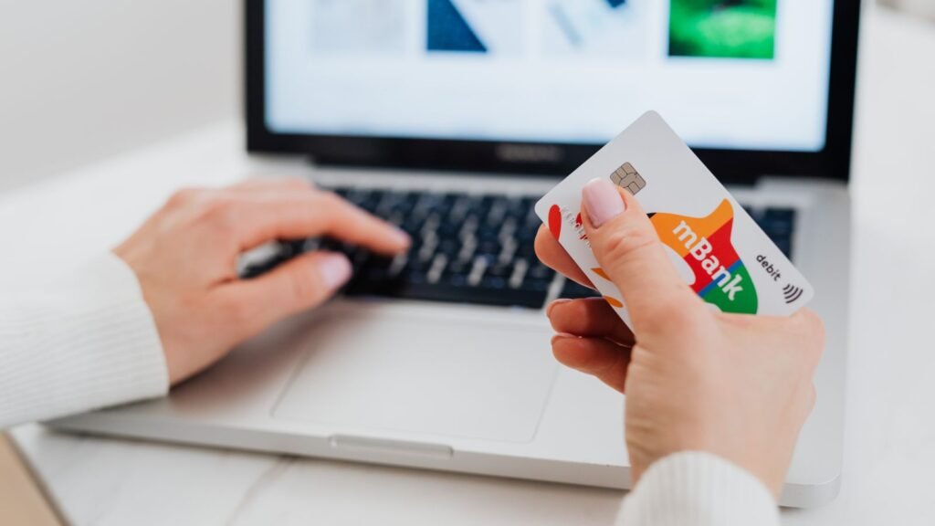Carte bancaire tenue devant un clavier d’ordinateur