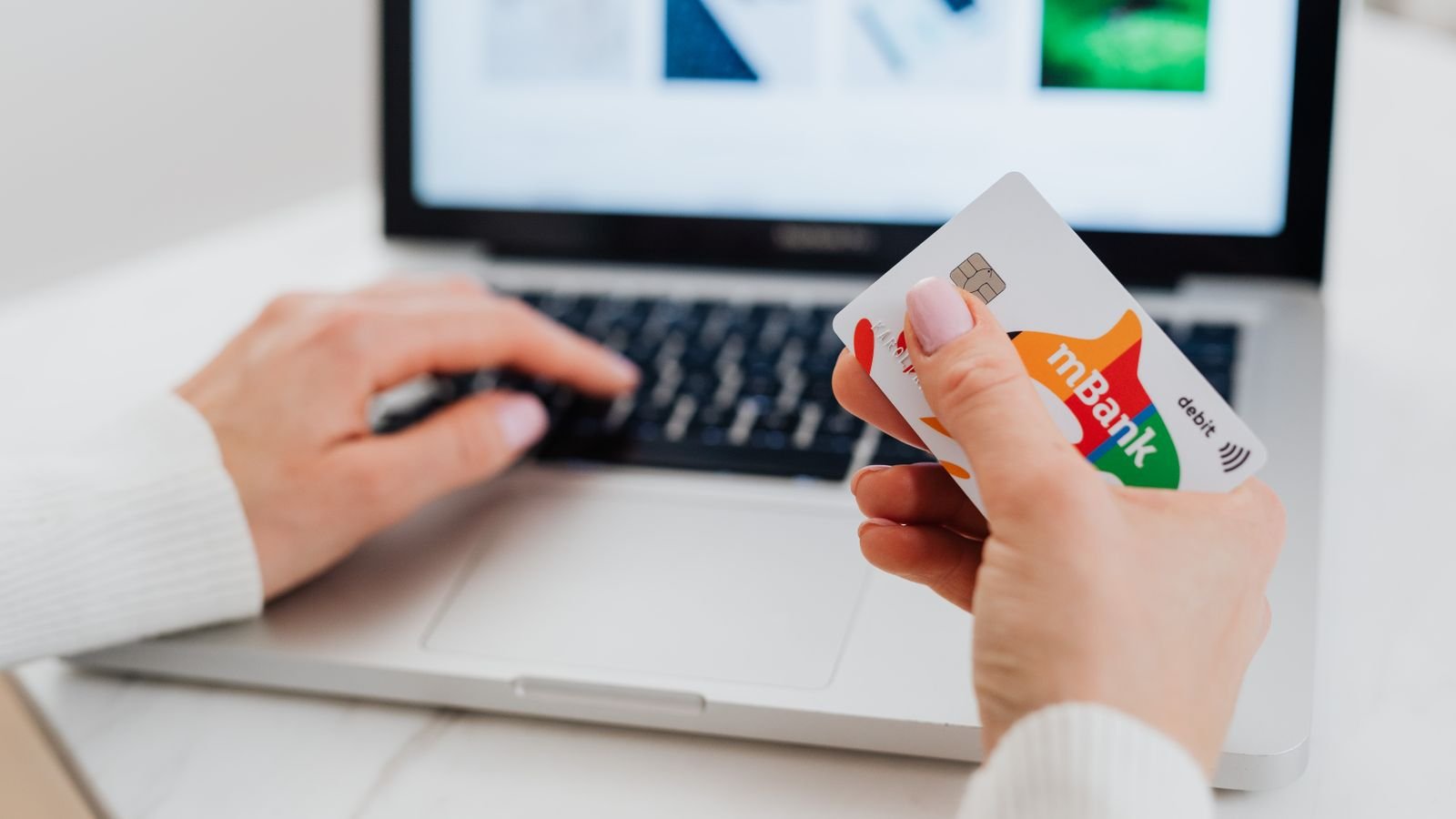 Carte bancaire tenue devant un clavier d’ordinateur