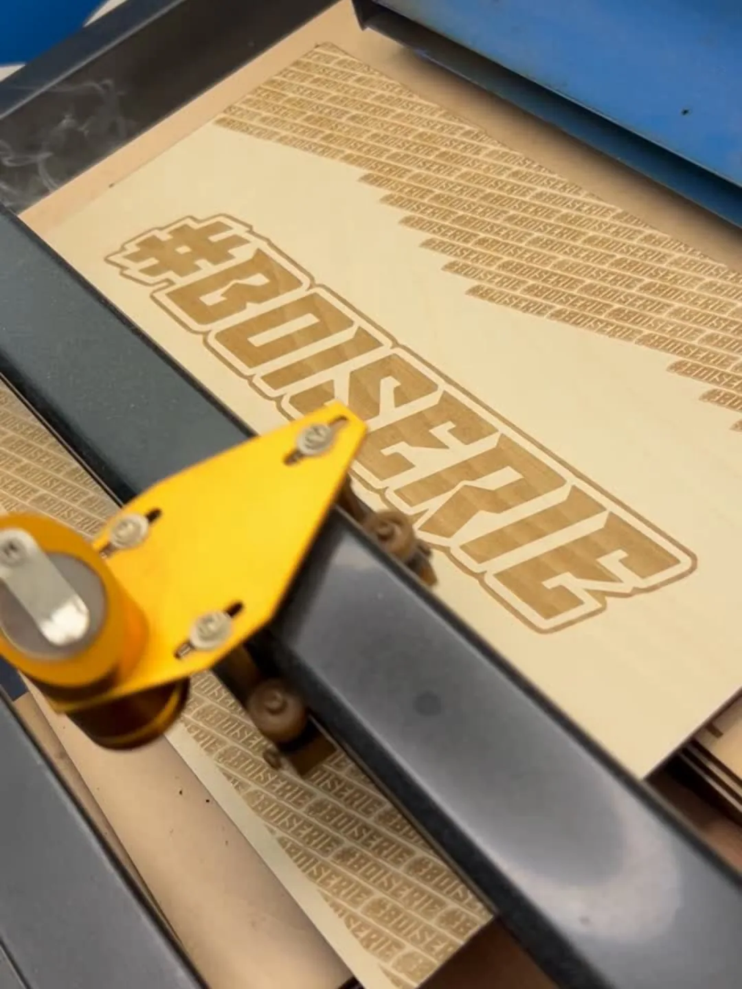 Graveuse laser en train de graver une plaque de bois pour un concours