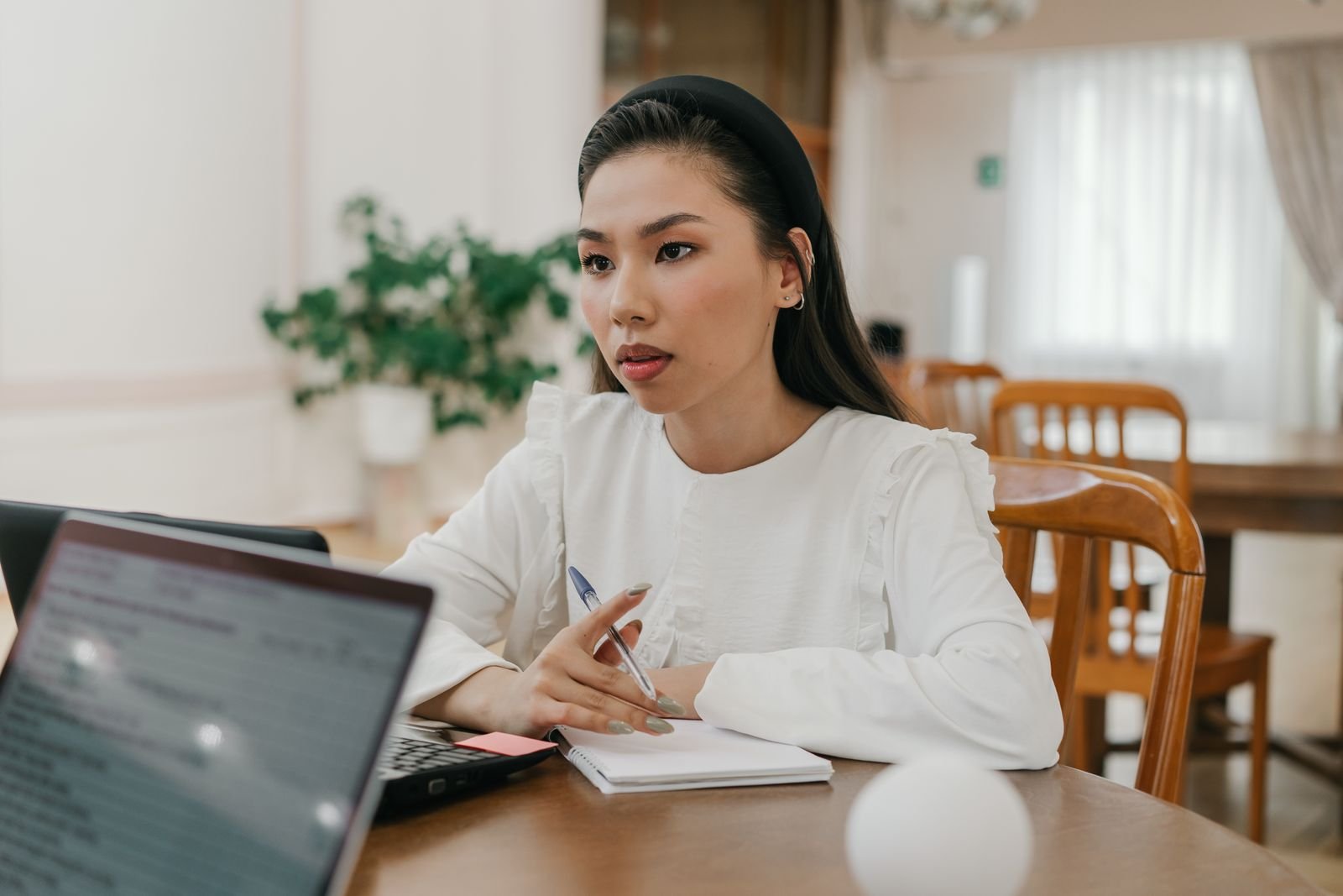 Jeune femme prenant des notes sérieusement devant son ordinateur portable