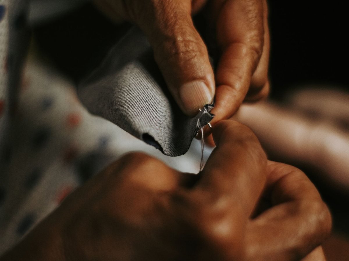 Des mains cousent un tissu avec du fil et une aiguille