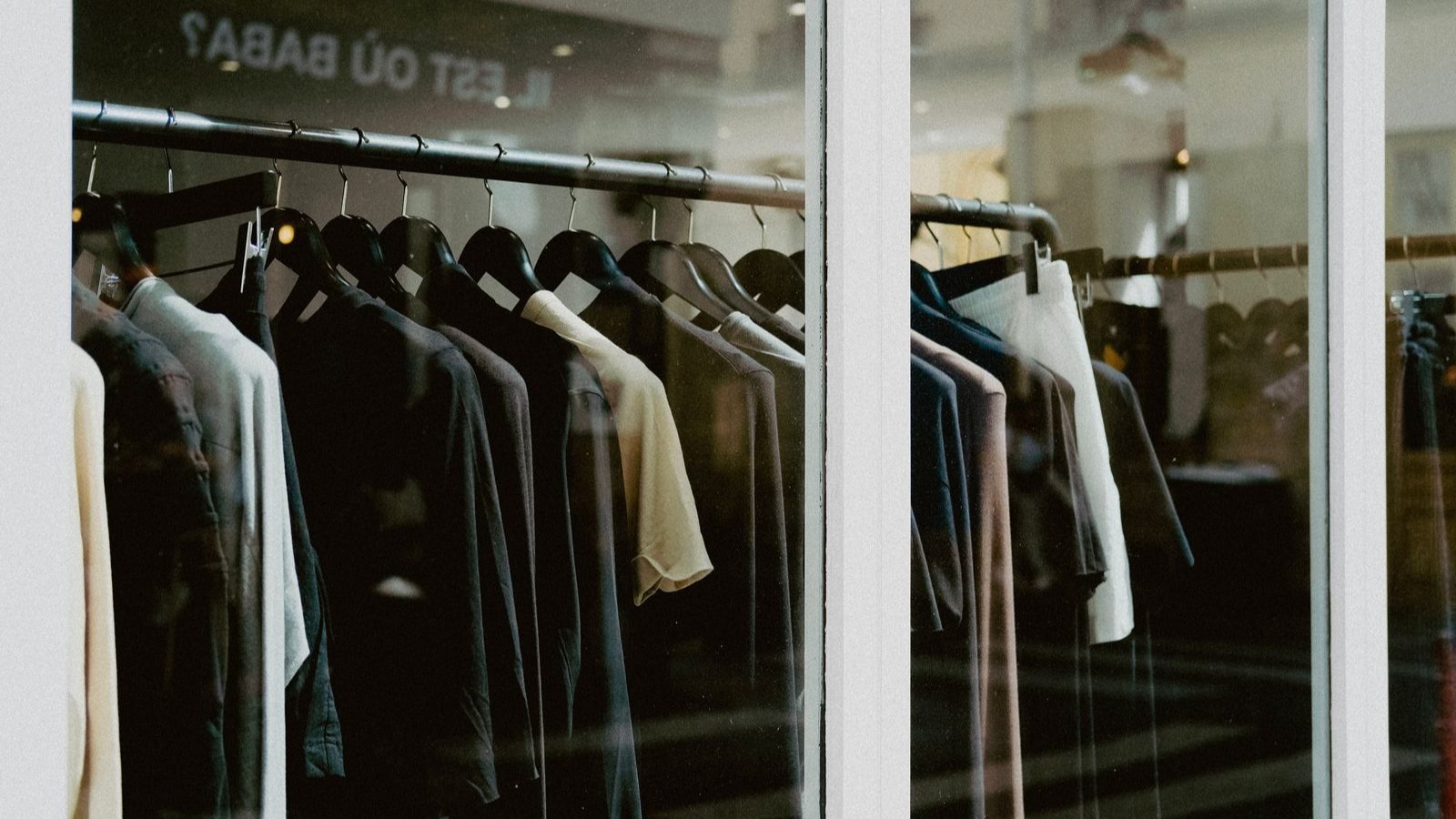 Des vetements sur cintres alignes dans une boutique