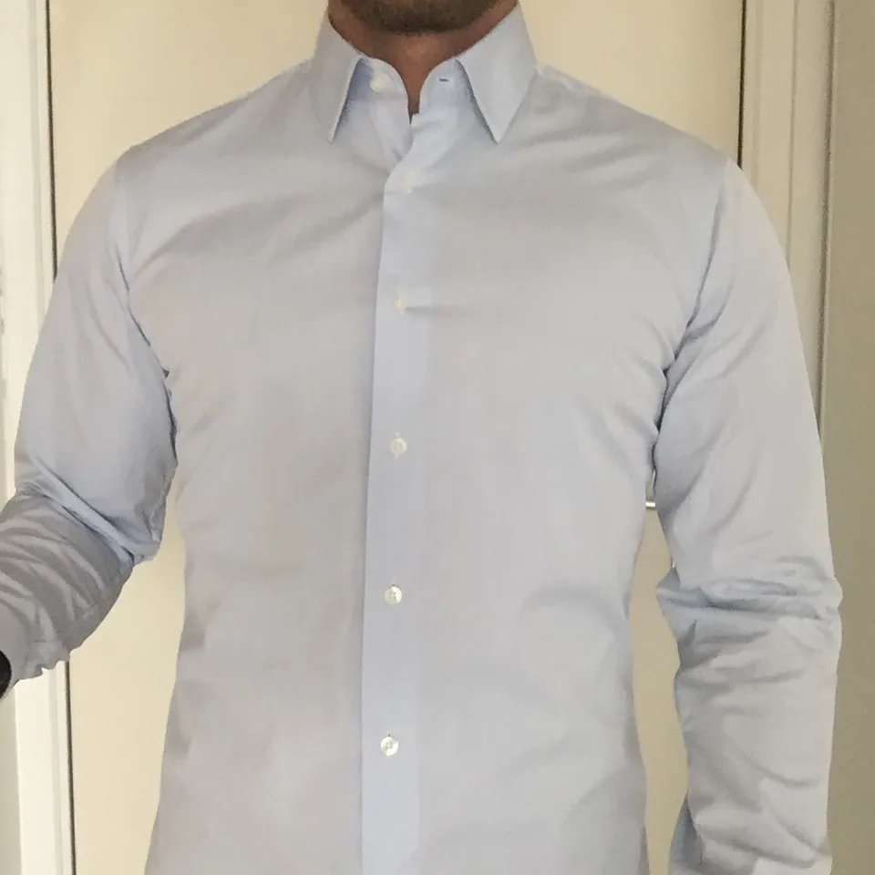Chemise en coton bleu ciel portée de face, col fermé et patte de boutonnage
