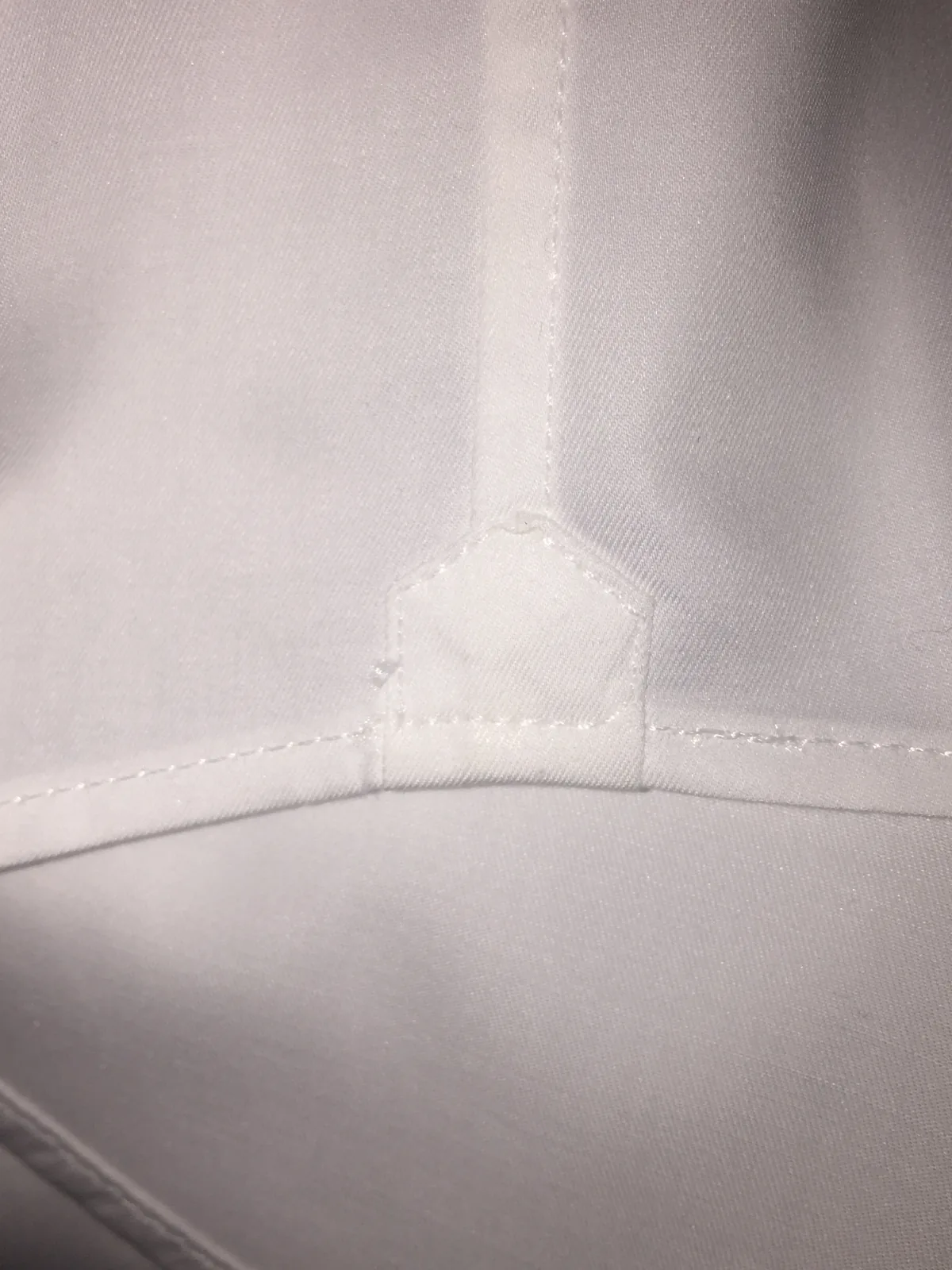 Gousset pentagonal de renfort en bas de la fente latérale d’une chemise blanche