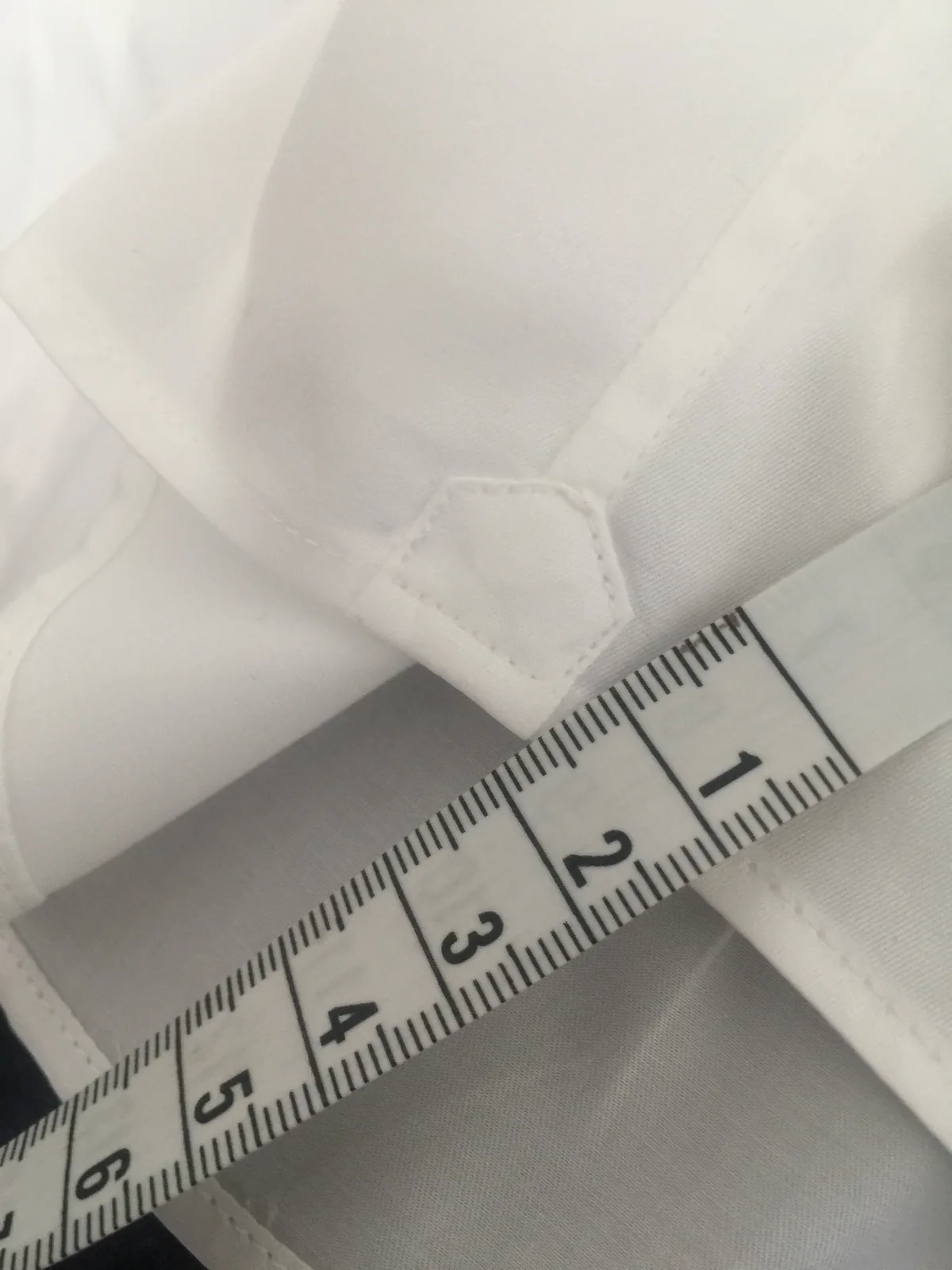 Gousset de renfort mesuré au mètre ruban sur la fente latérale d’une chemise