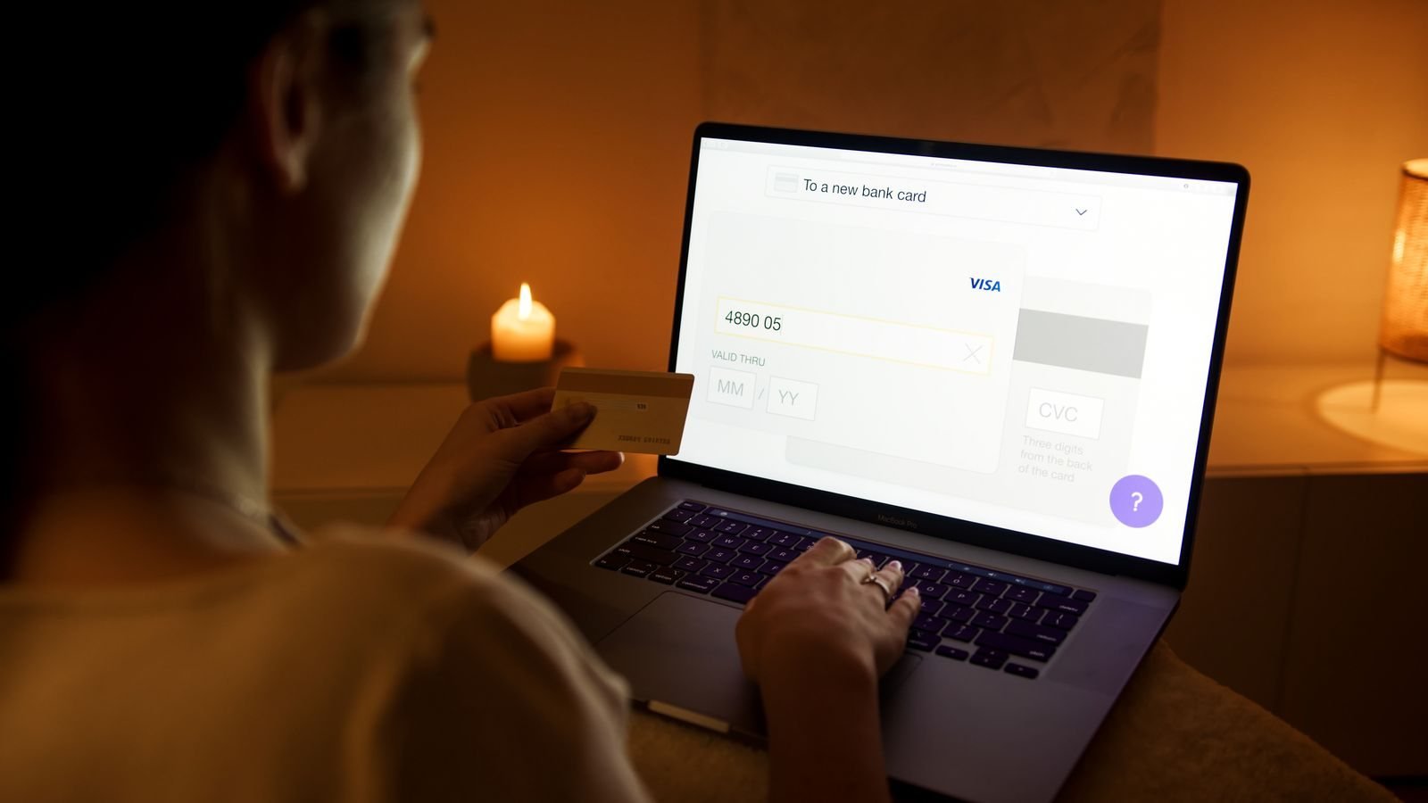 Une femme effectue un paiement en ligne avec sa carte bancaire devant un ordinateur