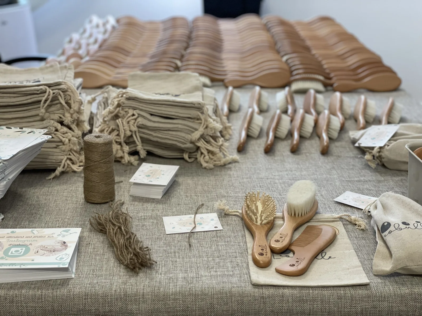 Brosses pour bébé alignées avec pochons en coton et cartes de marque, prêtes au conditionnement