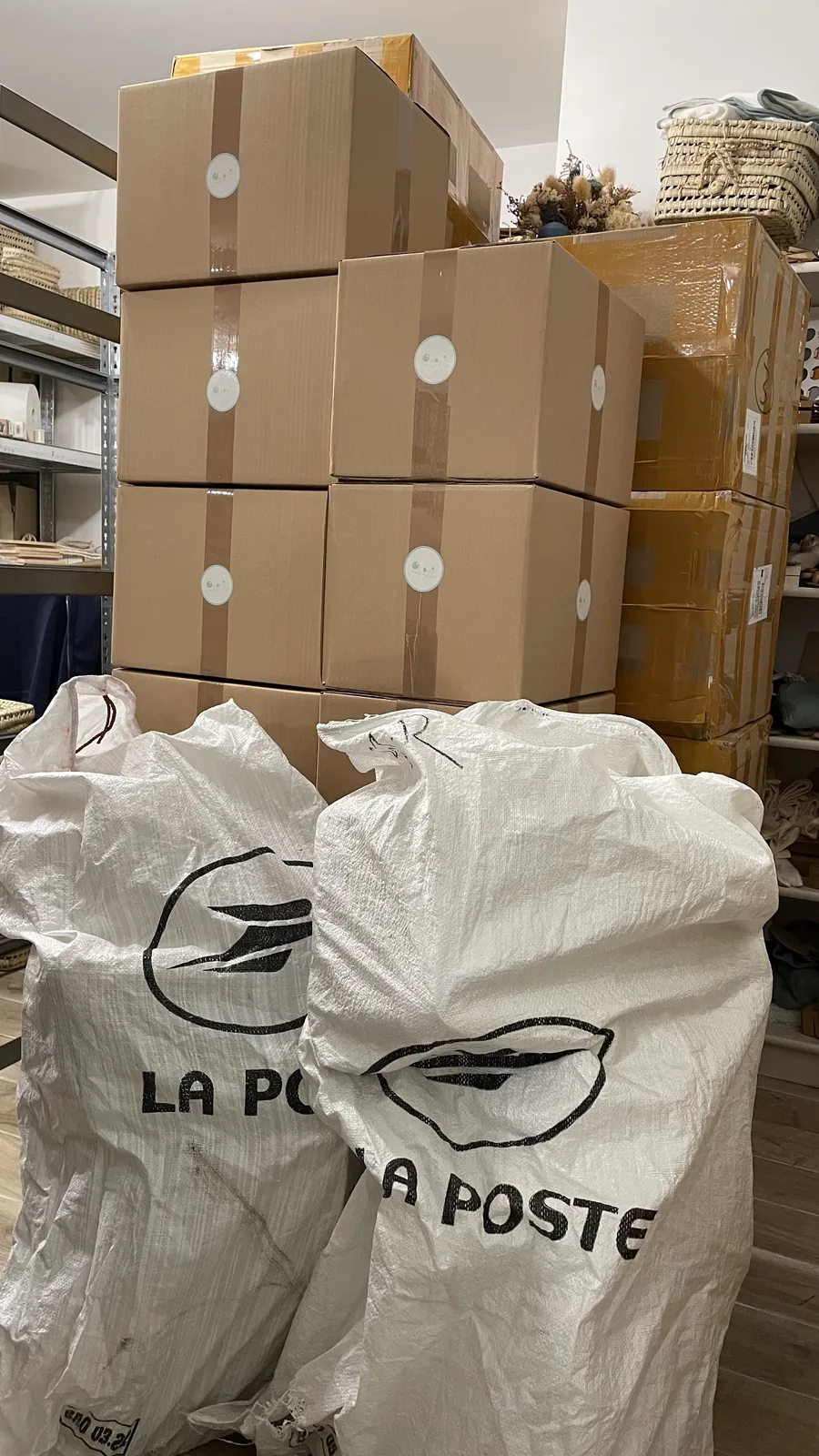 Cartons de réapprovisionnement empilés à côté de deux sacs postaux dans un atelier