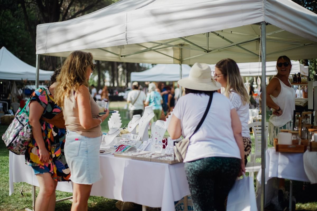 Des visiteurs parcourent les stands de bijoux dans un marché en plein air animé