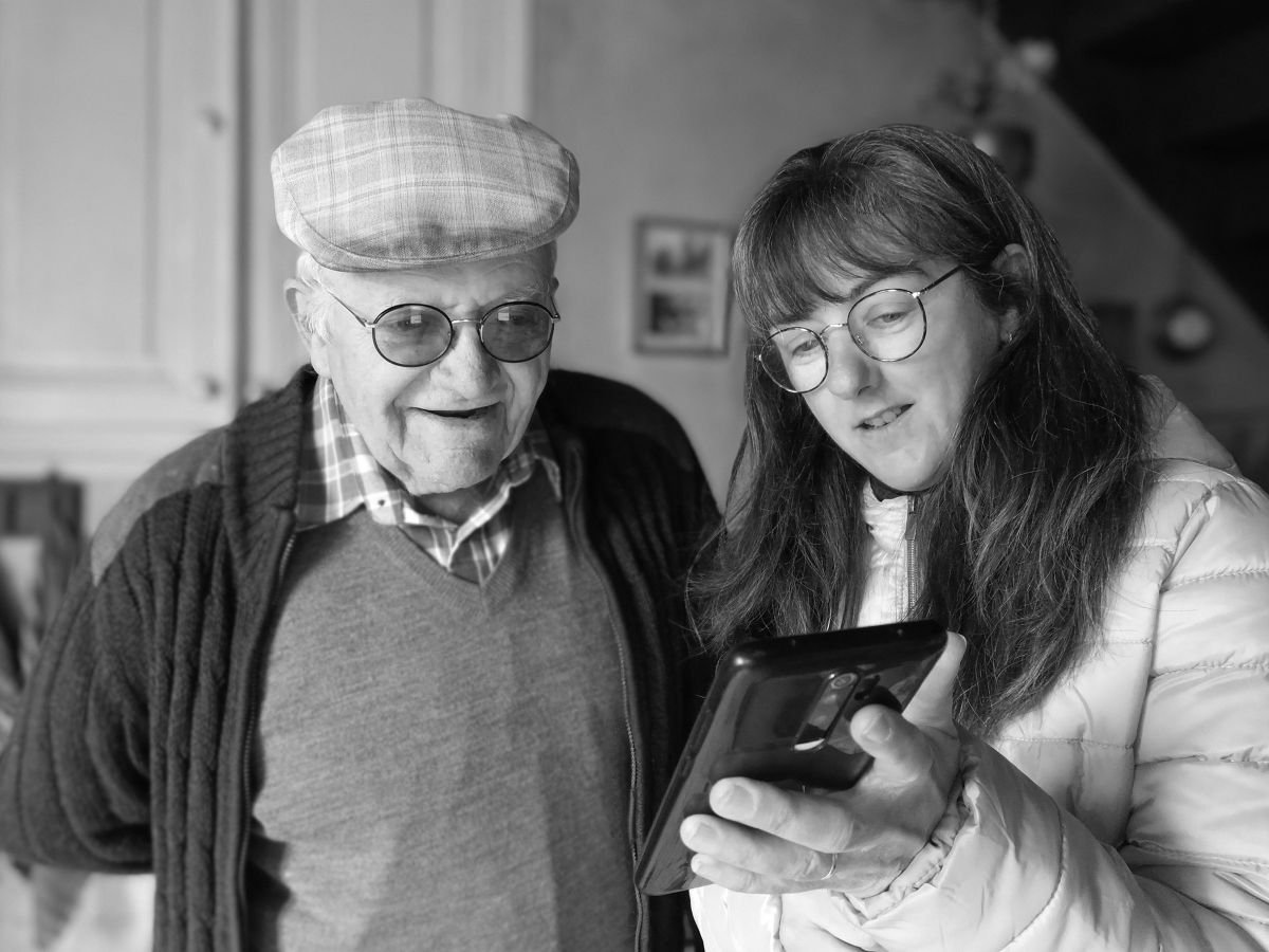 Un homme et une femme âgés ensemble regardant un smartphone à l'intérieur