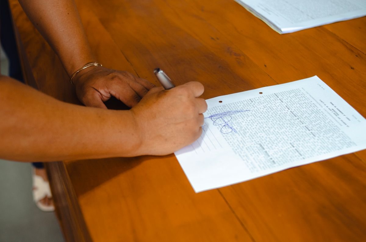Gros plan de mains signant un document juridique sur une table en bois à
