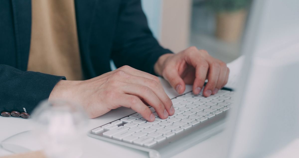 Gros plan sur des mains tapant sur un clavier blanc dans un environnement de