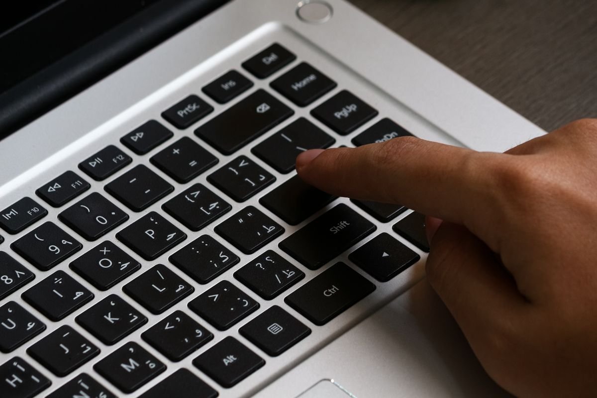 Une personne tapant sur un clavier d'ordinateur portable avec du texte arabe