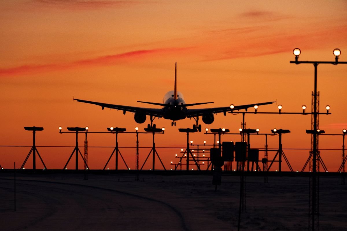 Une silhouette d'un avion atterrissant au coucher du soleil