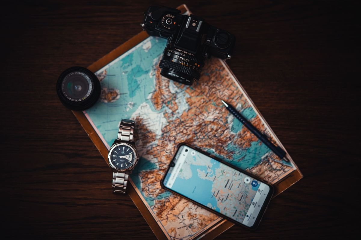Vue du dessus des essentiels de voyage comprenant une carte, un appareil photo