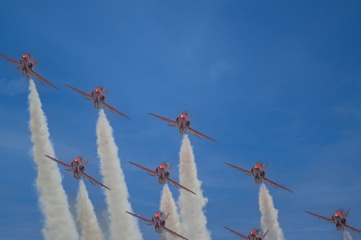 Formation de jets acrobatiques s'élevant dans un ciel bleu clair, créant des