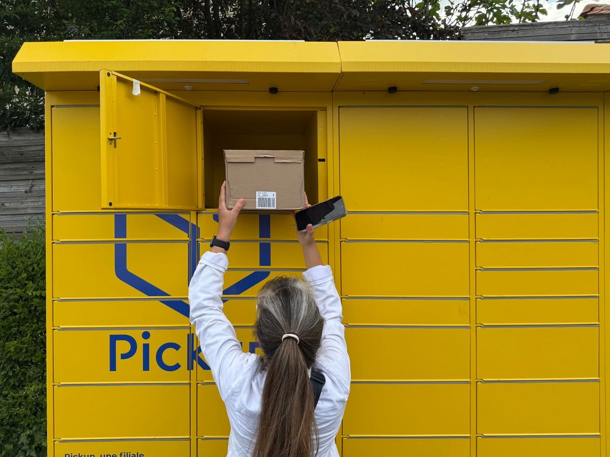 Une femme utilisant un casier à colis jaune pour récupérer un colis à