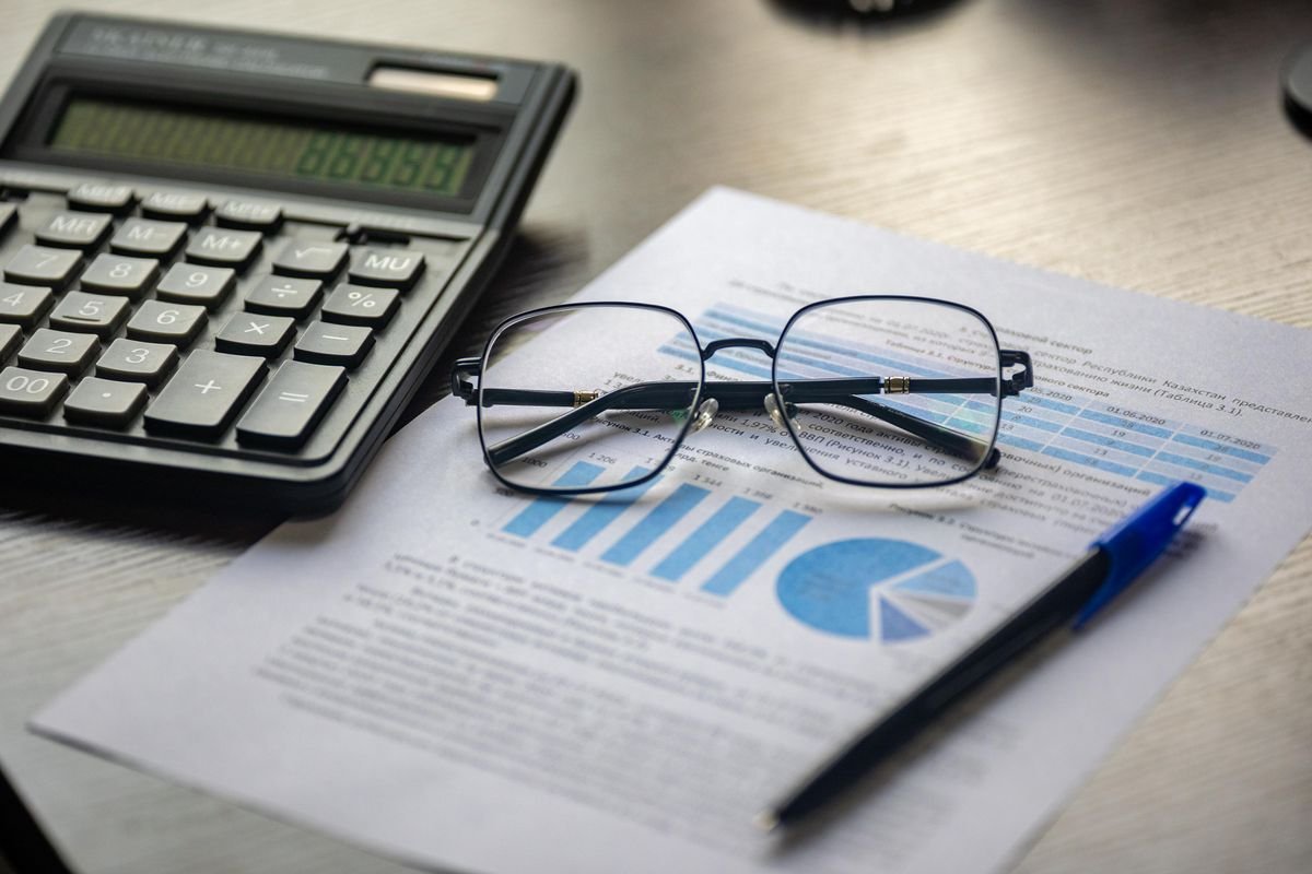 Document financier avec une calculatrice, un stylo et des lunettes