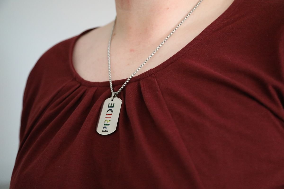 Vue rapprochée d'un collier Pride en argent porté sur une chemise marron