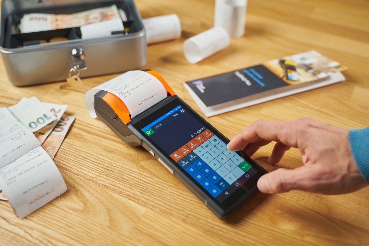 Personne utilisant un terminal de paiement numérique sur un bureau en bois avec
