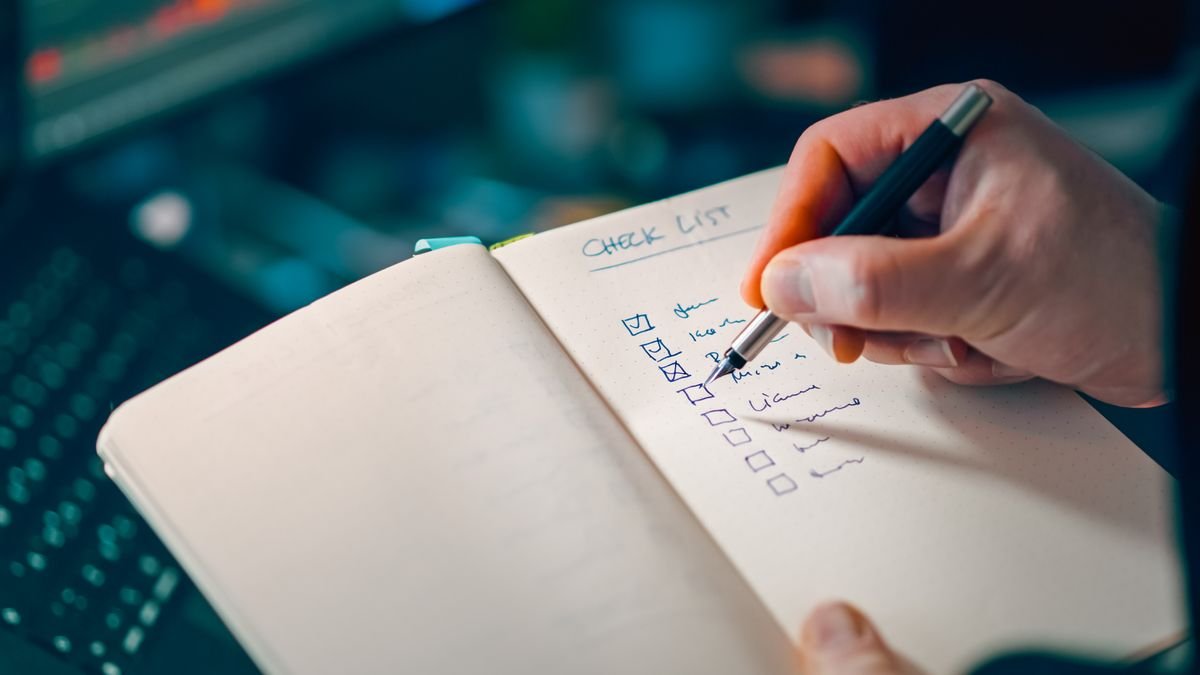 Gros plan sur une main écrivant dans un carnet contenant une liste de contrôle