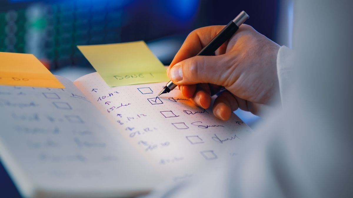 Gros plan sur une main écrivant dans un cahier à cases à cocher