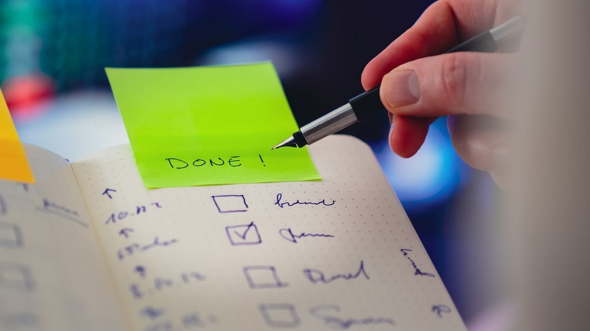Gros plan sur une liste de tâches et un stylo avec une note autocollante
