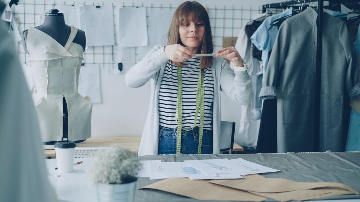 La fiche produit qui vend (et qui est conforme) Une jeune créatrice de mode prend des mesures de tissu dans un studio moderne
