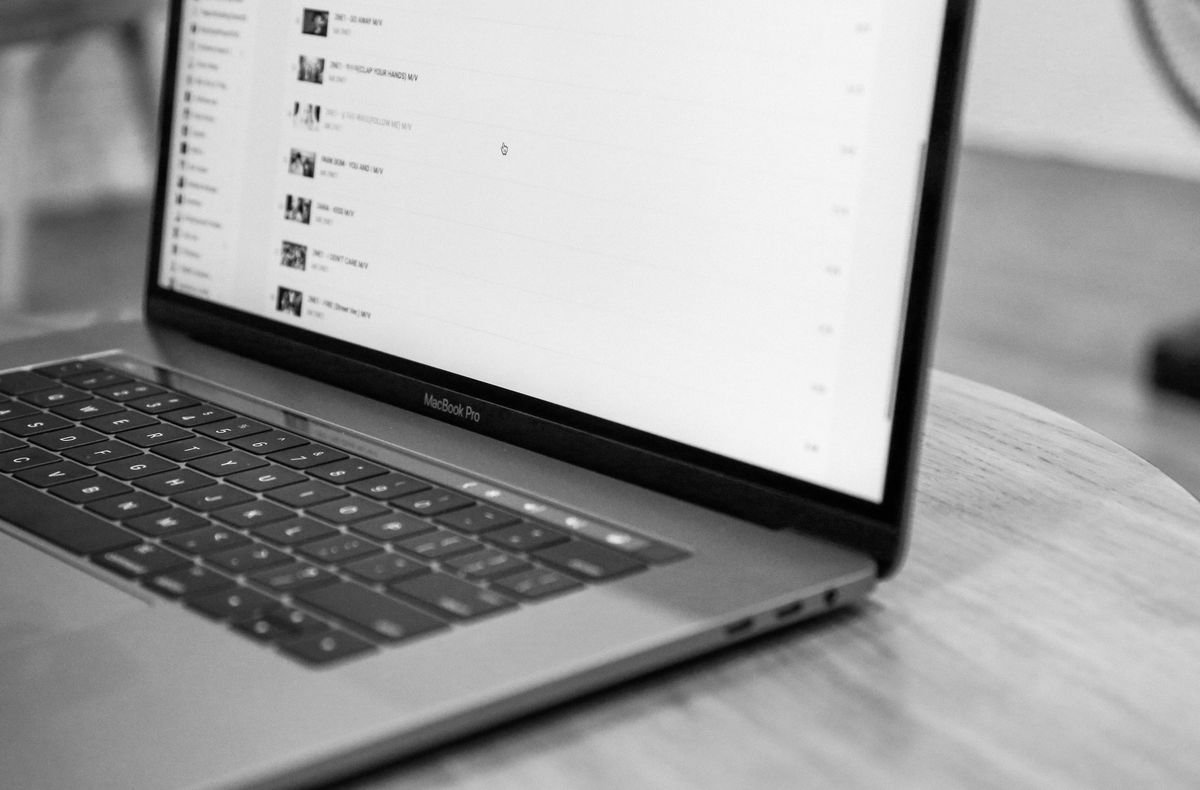 Photo en noir et blanc d'un MacBook Pro sur une table en bois ronde