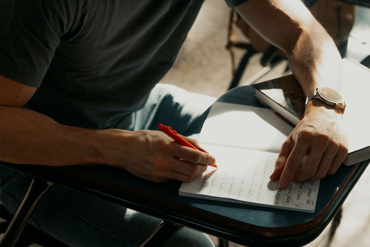 Élève concentré prenant des notes dans un cahier pendant le cours