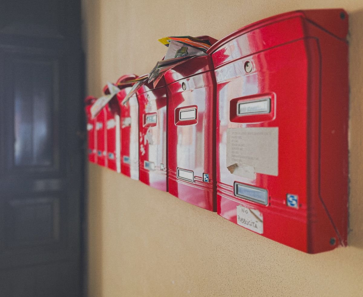La nouvelle taxe sur les petits colis, expliquée simplement Rangée de boîtes aux lettres rouges débordant de courrier