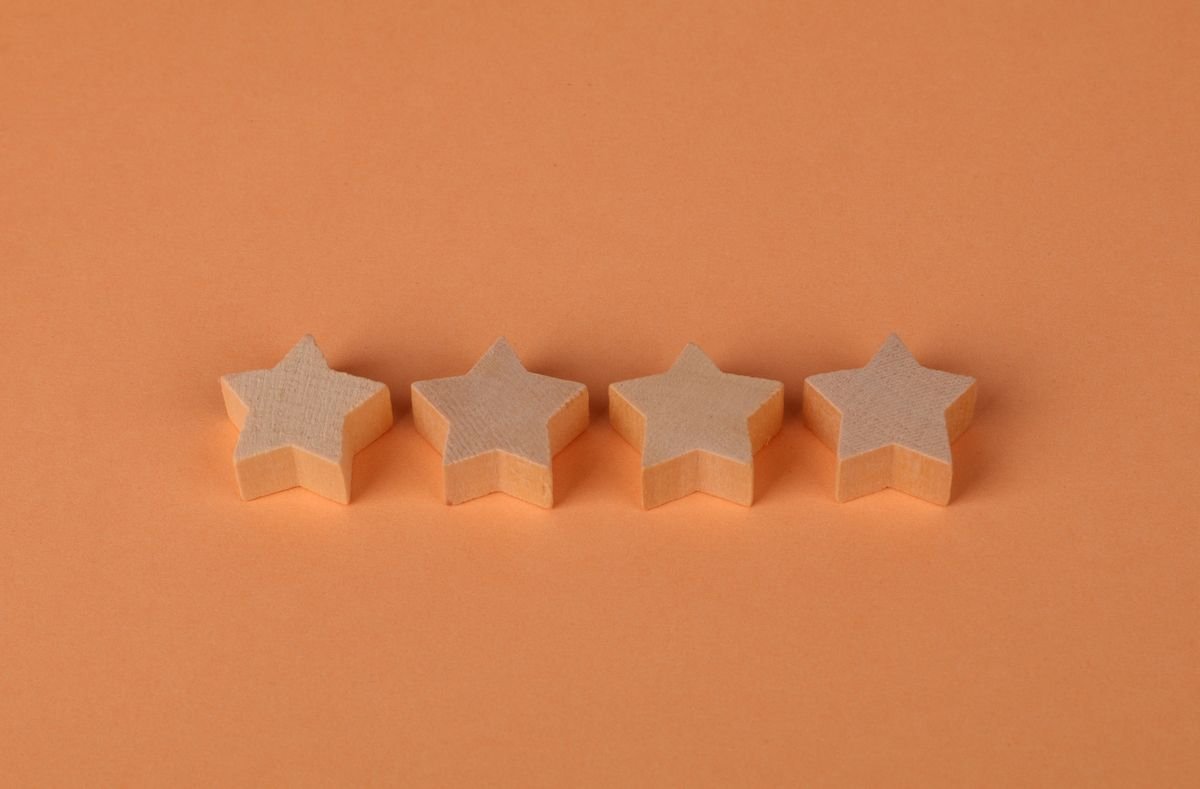 Les avis clients : ce qu’ils valent vraiment Quatre blocs en bois en forme d'étoile alignés sur une surface orange unie