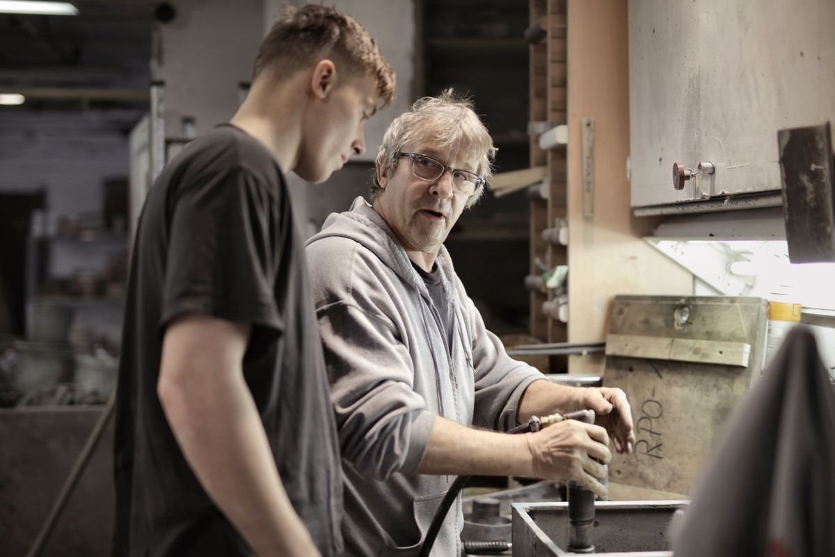 Artisan expérimenté instruisant un jeune apprenti dans un atelier industriel