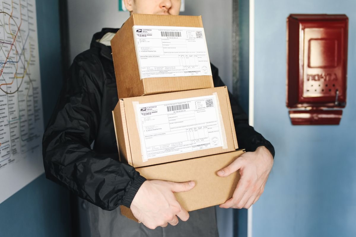 La nouvelle taxe sur les petits colis, expliquée simplement Un livreur transportant des colis en carton empilés pour un service de