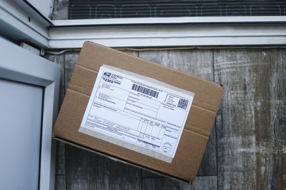 Le dropshipping vu de l’acheteur : le repérer, et vos droits Boîte en carton marron avec étiquette d'expédition sur le sol en bois près de