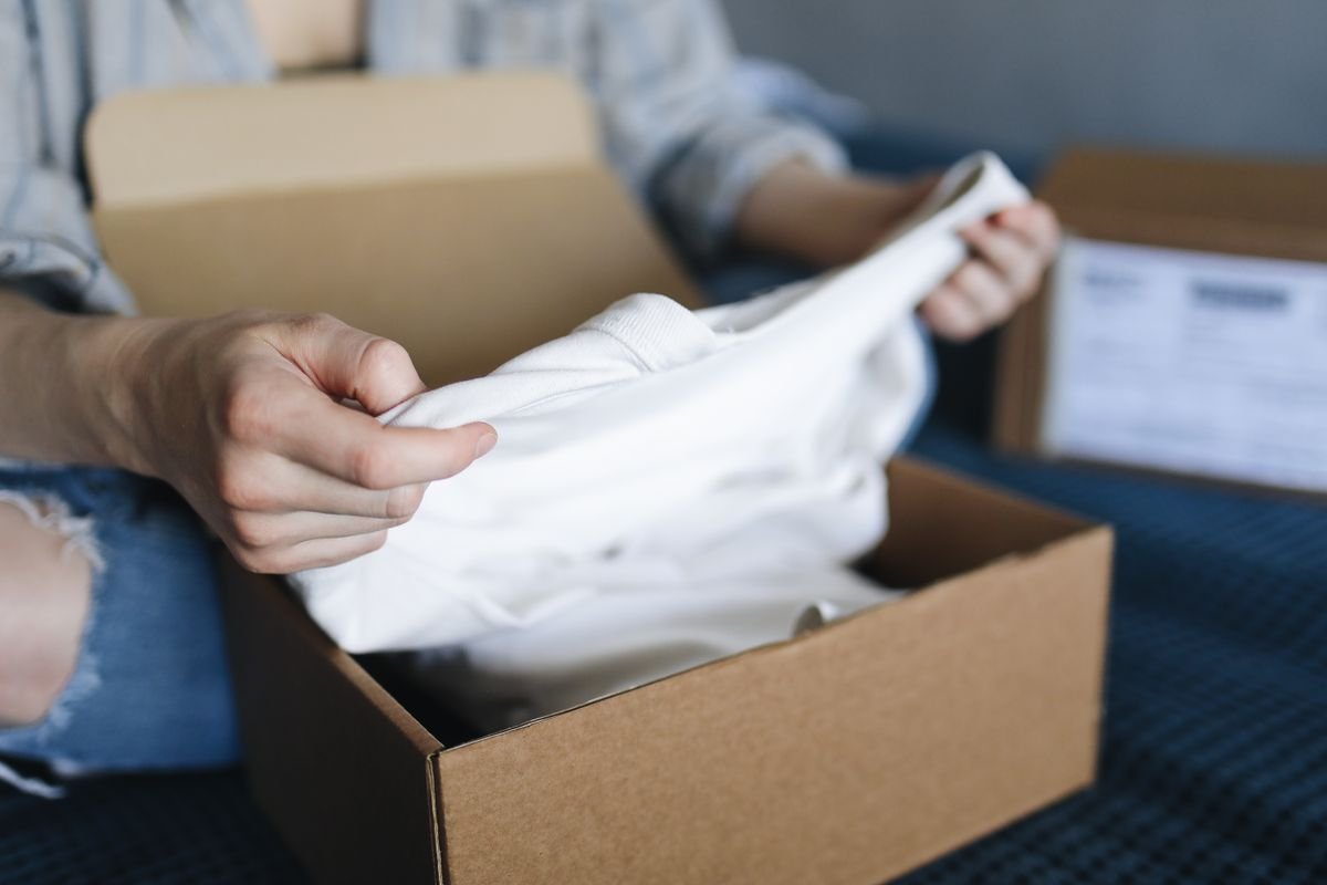 Gros plan sur une personne déballe un vêtement d'un colis en carton à