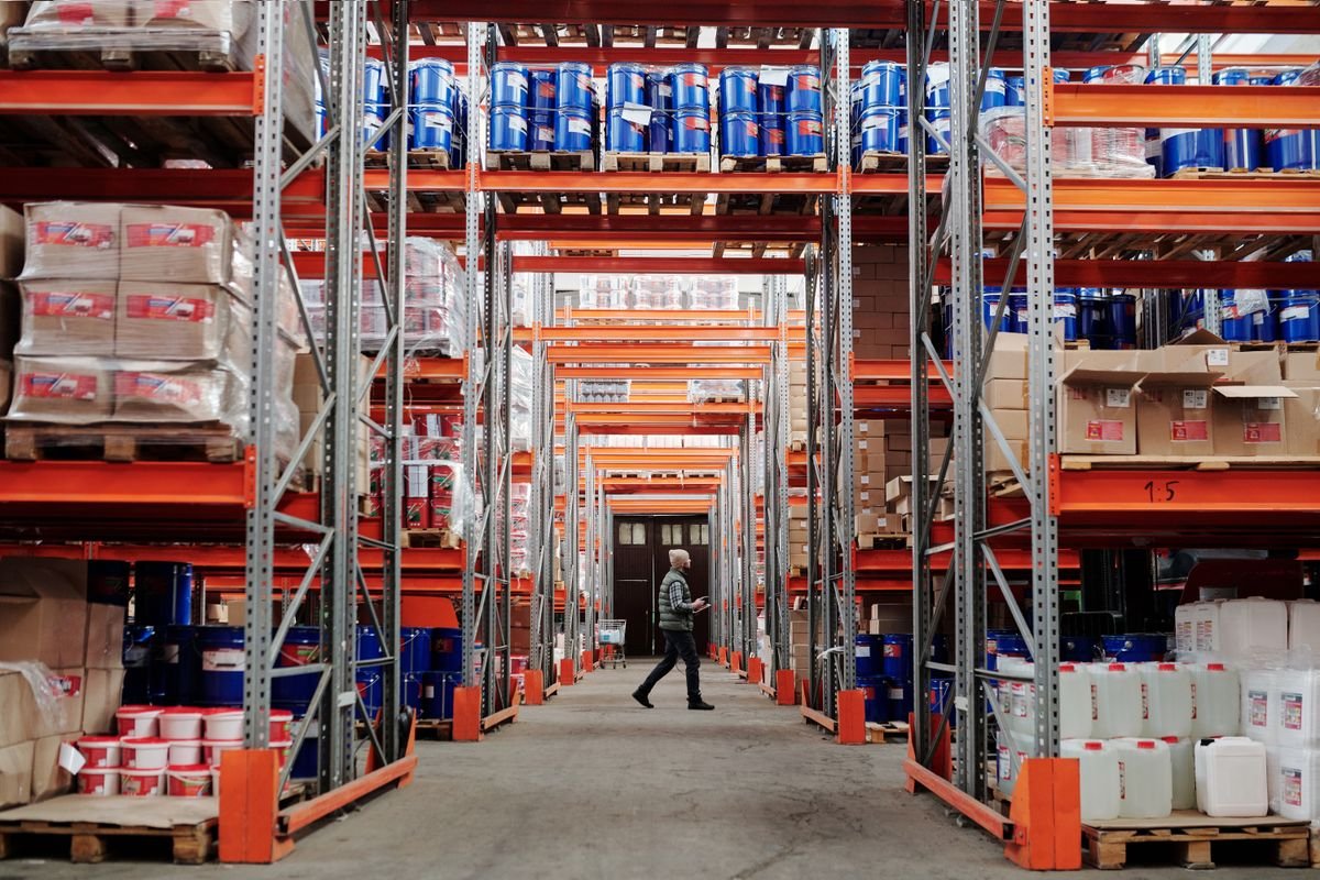 Un homme marchant à travers un grand entrepôt industriel avec des étagères