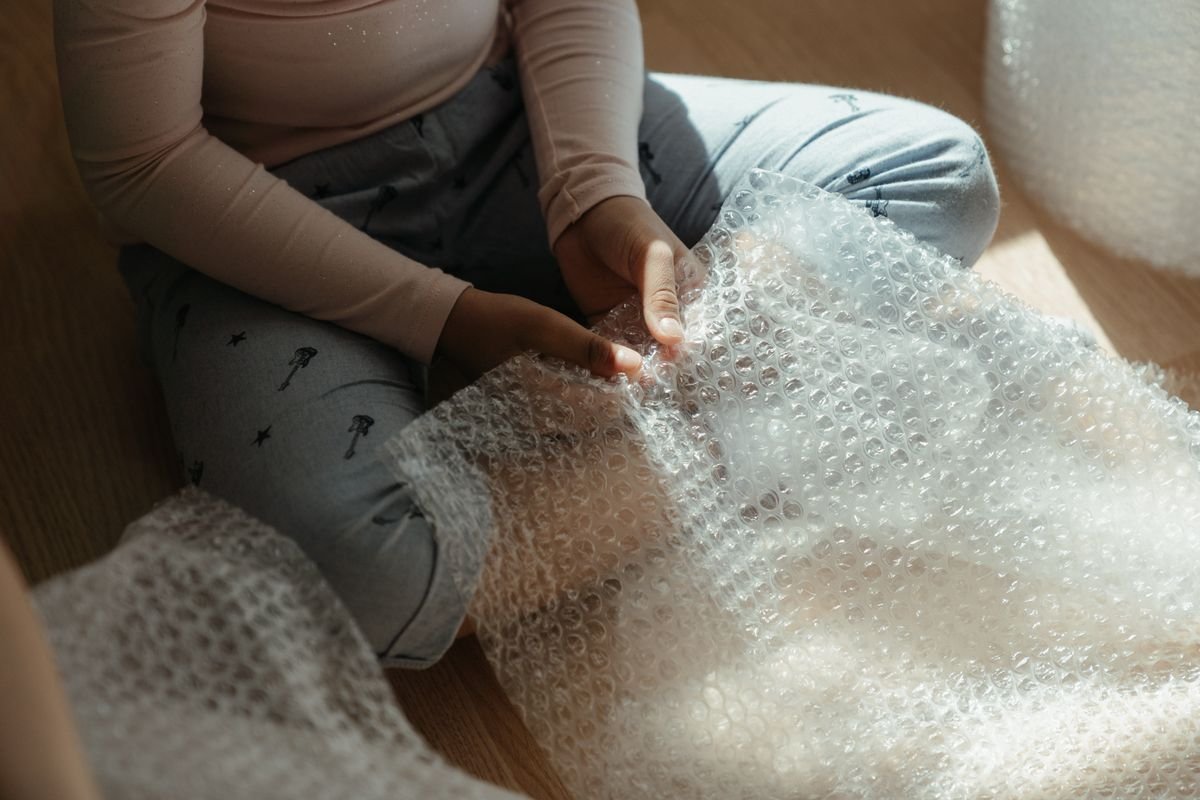 Le coût réel d’un colis : ce que personne ne compte Un enfant jouant à l'intérieur avec du papier bulle, profitant d'un moment de
