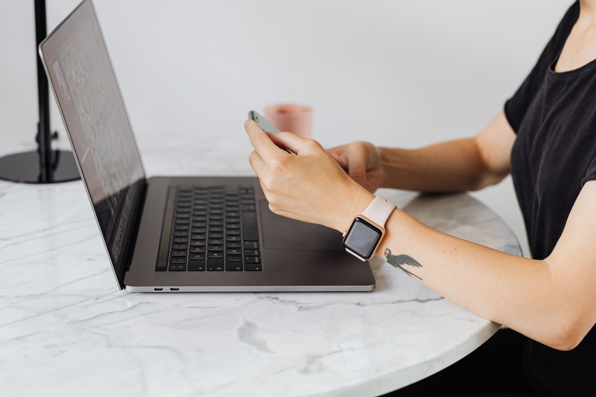 Adulte utilisant un smartphone et un ordinateur portable simultanément sur une