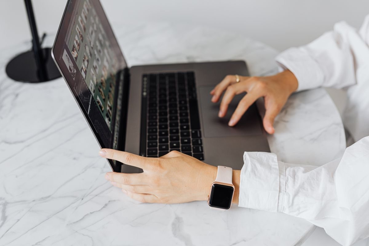 Choisir sa plateforme e-commerce : la méthode, pas le classement Personne tapant sur un ordinateur portable à une table en marbre, portant une