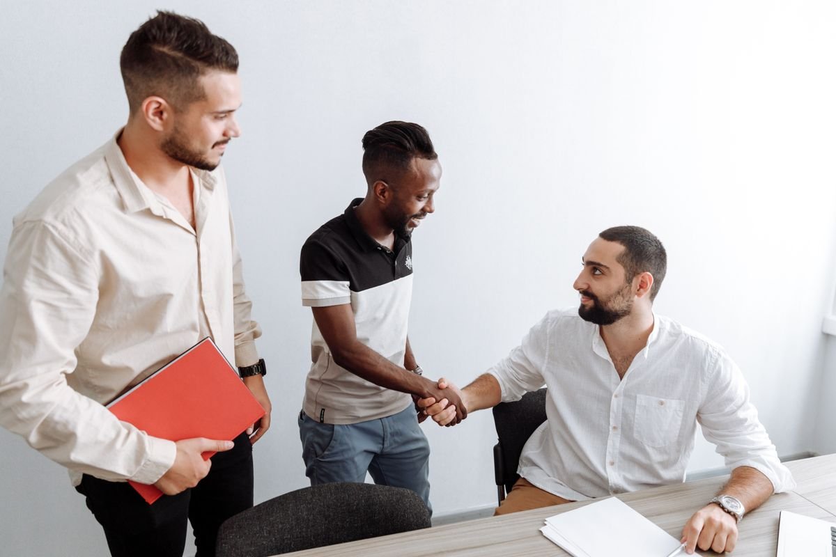 Trois hommes dans un bureau, se serrant la main
