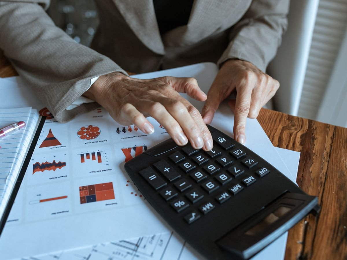 Le calcul de marge en e-commerce : de la vente à ce qui reste Des mains utilisent une calculatrice posée sur des tableaux chiffrés