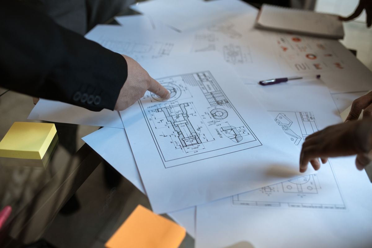 Des ingénieurs discutent de plans en blueprint dans un espace de travail, se