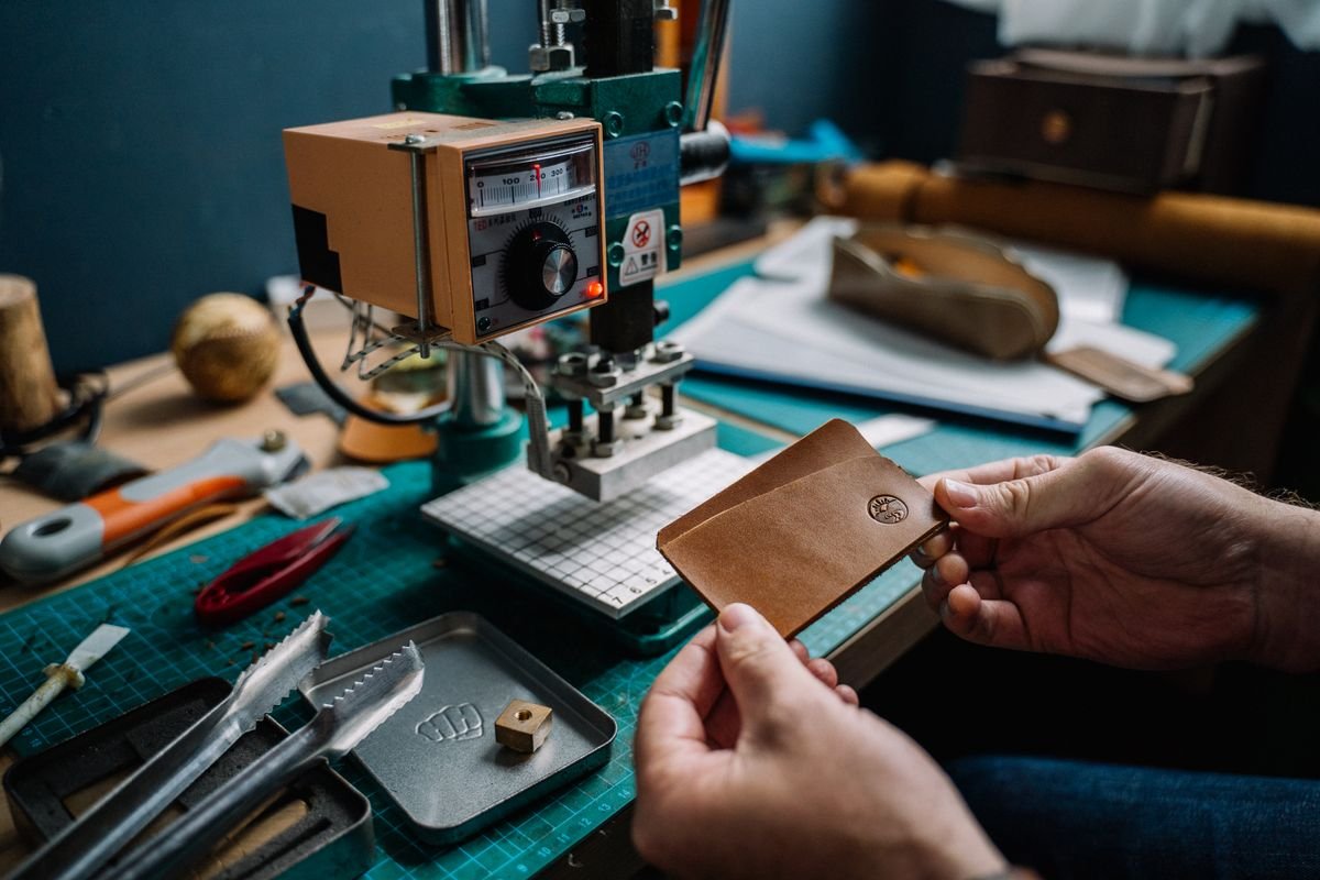 Gros plan d'un artisan créant un portefeuille en cuir fait main à l'aide d'une