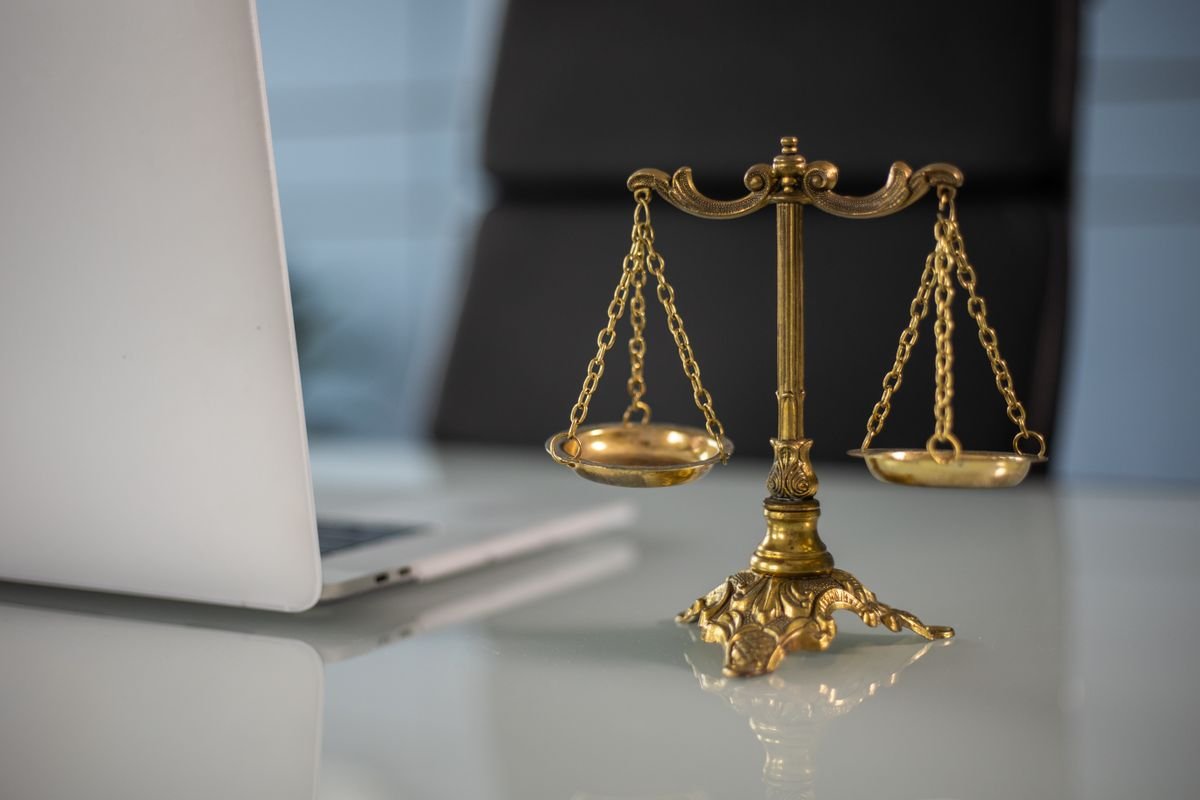 Médiateur de la consommation : l’obligation oubliée Des balances de justice dorées sur un bureau à côté d'un ordinateur portable